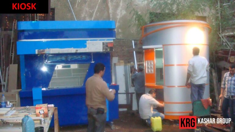 Mobile Solutions Kiosk construction: Modern silver and orange kiosk next to a blue machine