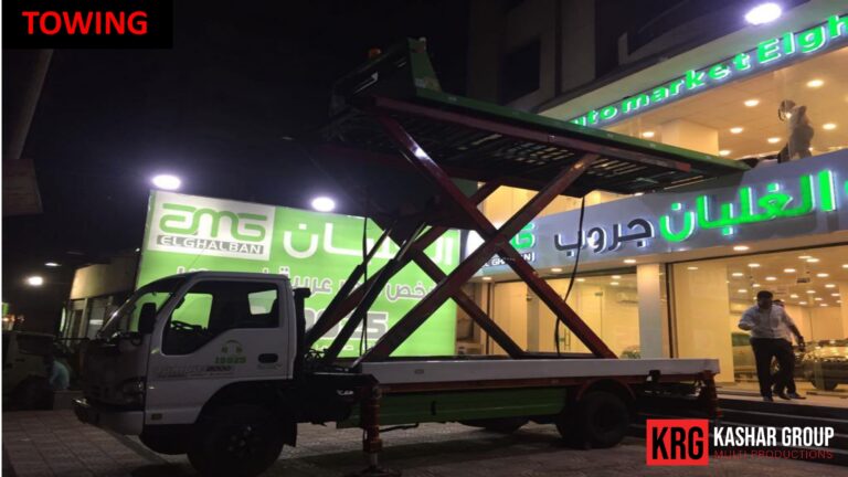 Mobile Solutions Towing truck with a raised car carrier at night, "TOWING" text visible