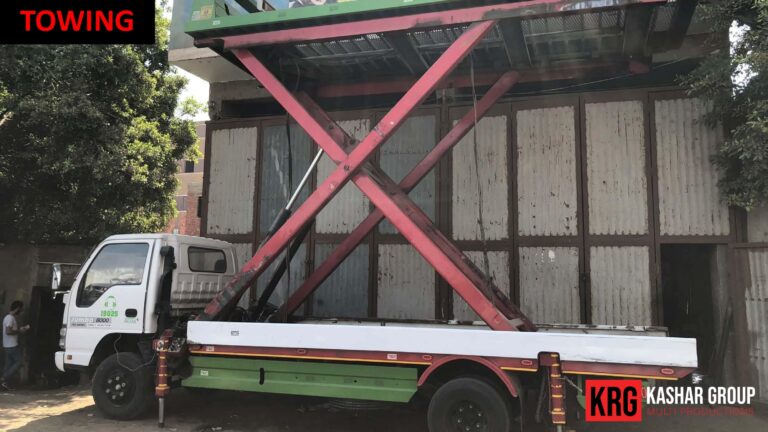 Mobile Solutions White truck towing a large red scissor lift with "TOWING" text