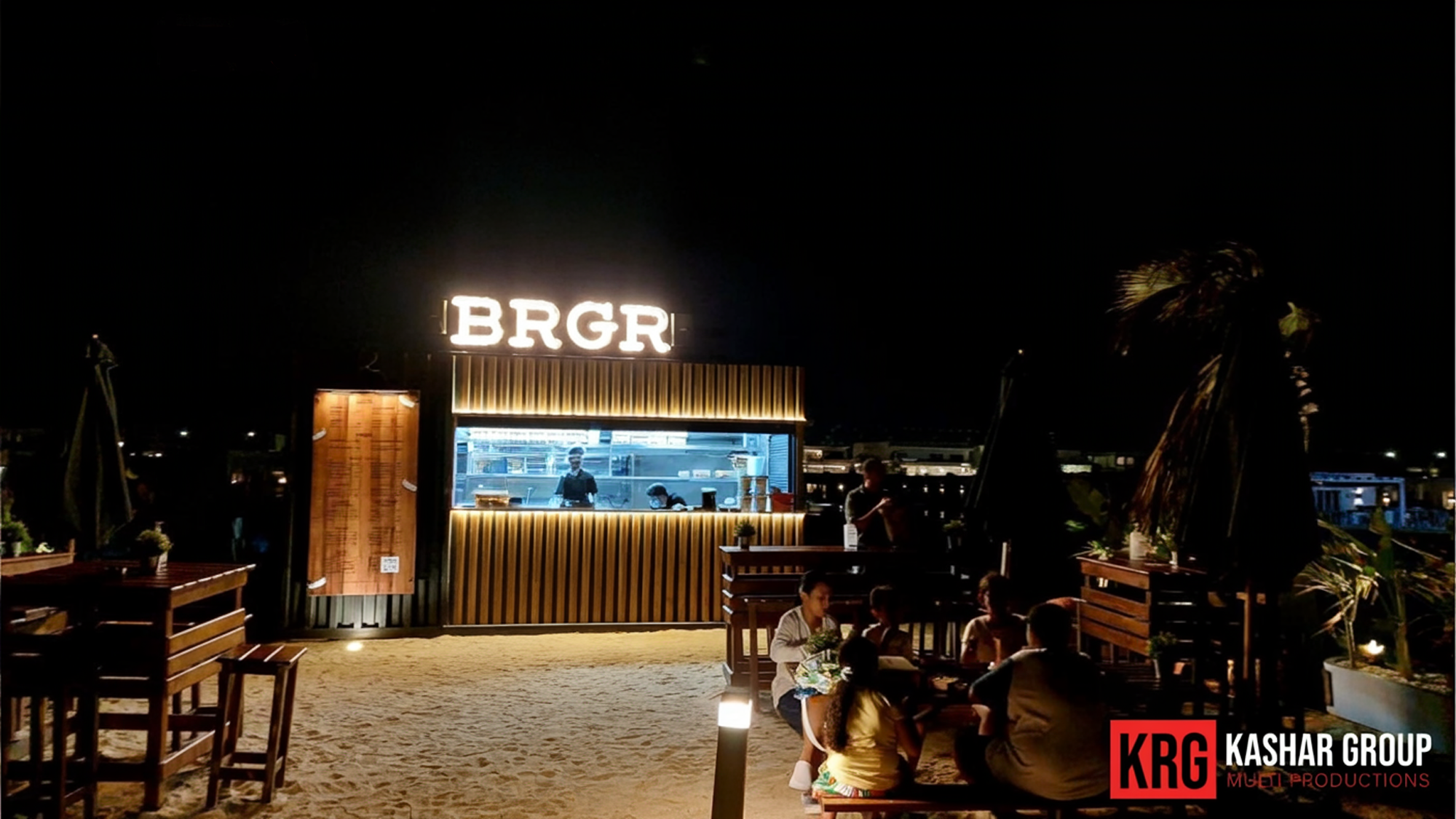 Mobile Solutions BRGR food stand at night with people dining on the beach